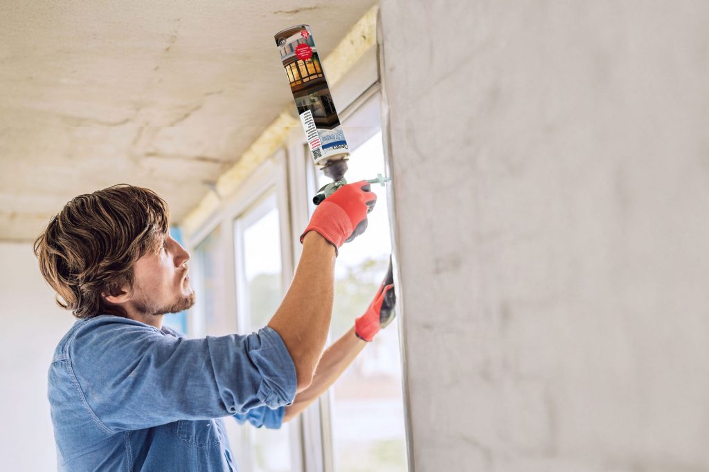 Mann in einem blauen Hemd und roten Handschuhen macht Fensterinstallation. Mit einem ClearoPAG 167plus PU-Montageschaum.